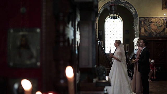 在法国尼斯的东正教教堂里，新娘和新郎手持蜡烛站在婚礼上。伴郎和伴娘在未婚夫身后祝福。希腊东正教的仪式、传统和习俗视频素材