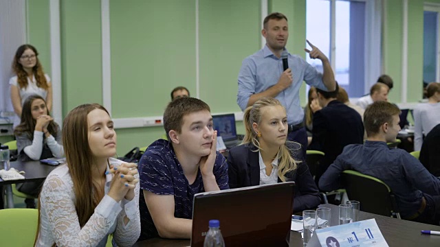 一组年轻的企业家坐在桌子前，拿着笔记本电脑，准备向观众展示他们的新互联网创业公司视频素材
