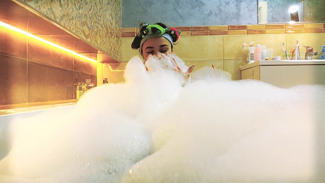 漂亮的黑发女人在泡澡，玩着肥皂泡沫。FullHD视频视频素材