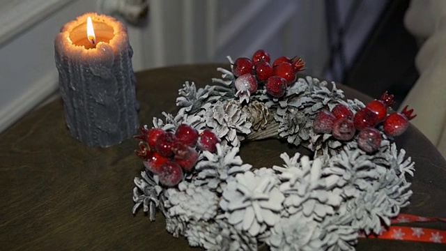 桌上放着圣诞花环和燃着的蜡烛。很快假期视频下载