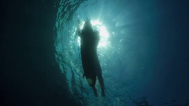 水下慢动作:男性冲浪者在开放水域的海浪上划桨视频素材