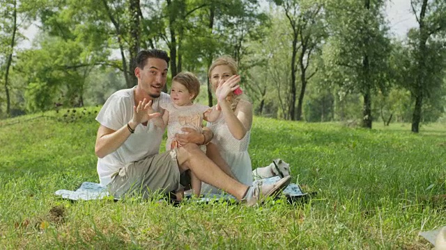 特写:可爱的父母和美丽的女婴坐在毯子上的公园视频素材