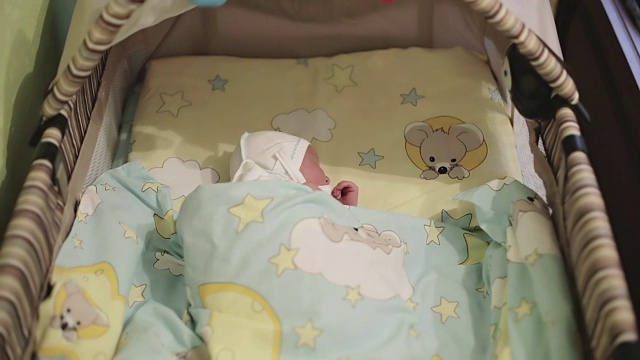 一个新生儿躺在孩子们的床上。视频下载