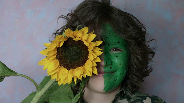 一个可爱的孩子用彩色脸和向日葵摆姿势的4k照片视频下载