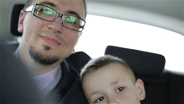 缓慢的运动。一个戴眼镜的帅哥和一个小男孩坐在车里。视频下载