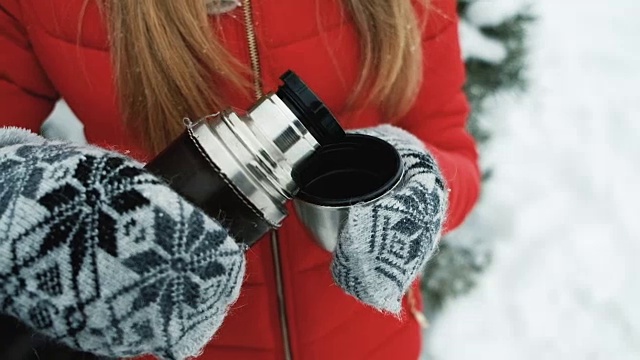 年轻女子在霜冻的室外用保温瓶泡茶取暖视频下载