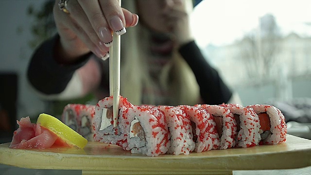 近距离观察在日本餐馆用筷子吃寿司的年轻女孩视频素材