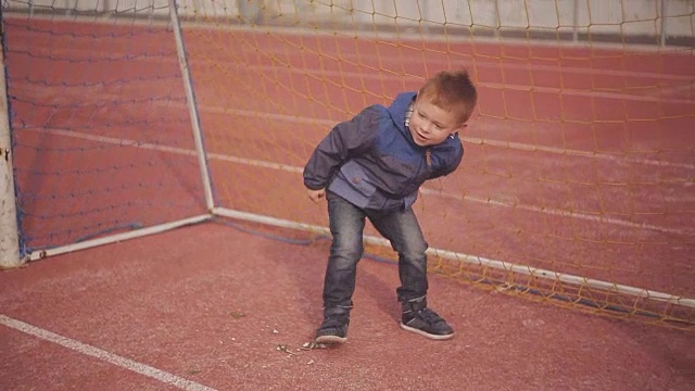 兴高采烈的红头发小男孩在体育场的一个足球门柱附近玩球视频素材