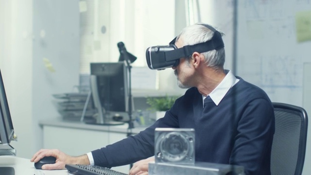 虚拟现实工程师戴着虚拟现实眼镜同时在他的个人电脑上编程。视频下载