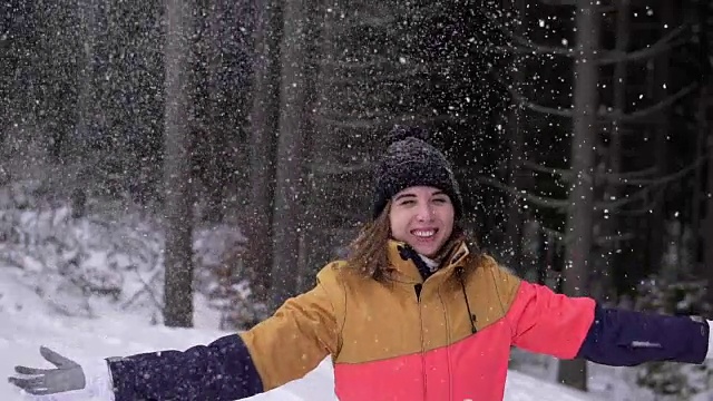冬天的风景美丽的雪花快乐的女人玩着飘落的雪花。年轻的女孩玩扔雪玩在外面与手臂在空中嬉戏的冬天。视频下载