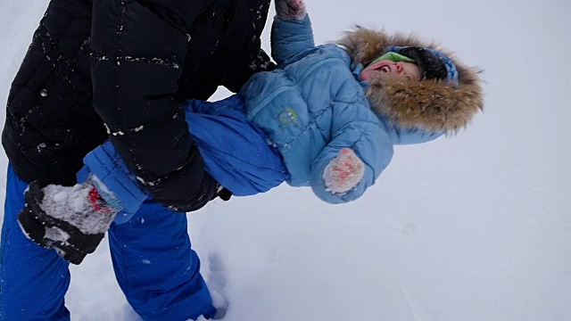 这家伙在冬季公园和宝宝玩。扔雪视频下载