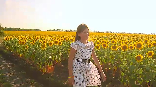 少女走过黄花田，少女在黄花田微笑，金色的向日葵花随风摇曳。视频下载