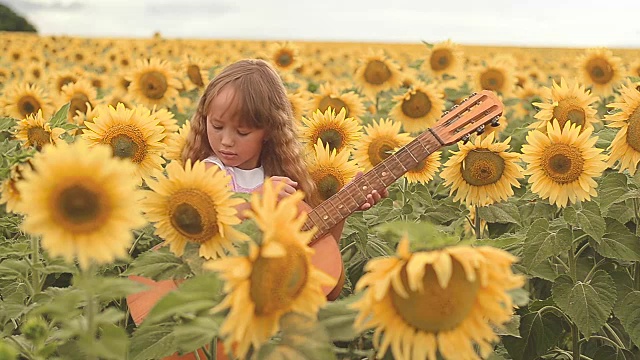 夏日的户外，小女孩在田野上弹奏吉他，背景是向日葵视频下载