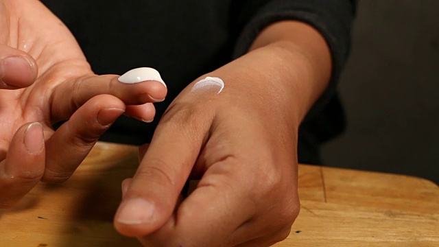 特写亚洲女性的手握和使用保湿霜。视频下载
