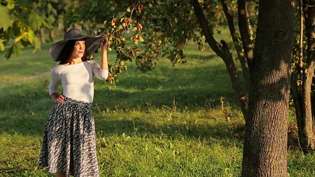 美丽诱人的女孩放松在温暖的夏天阳光照射下，一个美丽的绿色水果花园视频下载