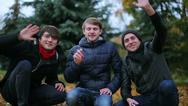 三个年轻的积极的男性青少年打招呼，向摄像机问好，开始skype电话视频下载