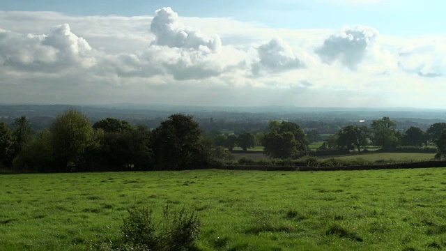 时间流逝拍摄的美丽的英国乡村与它的树篱，蓬松的云和绿色的田野与老橡树视频下载