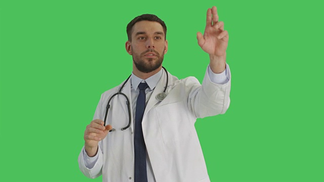 中景英俊的医生做滑动和触摸手势，而站在一个绿色屏幕背景。视频素材