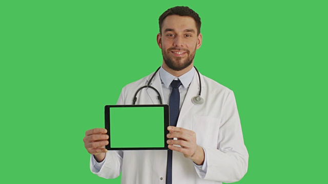 中景微笑的医生拿着水平平板电脑与绿色屏幕。背景中的绿色屏幕。视频素材