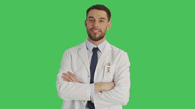中景一个英俊的医生/科学家交叉双臂在胸部。拍摄发生与绿色屏幕背景。视频素材