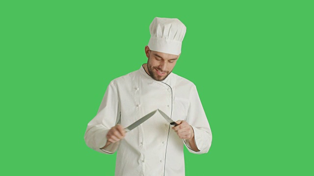 中景英俊微笑的厨师磨刀。背景为绿幕。视频素材