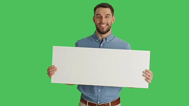 一个微笑的时尚男子拿着海报/海报的中镜头。在绿色屏幕上拍摄。视频素材