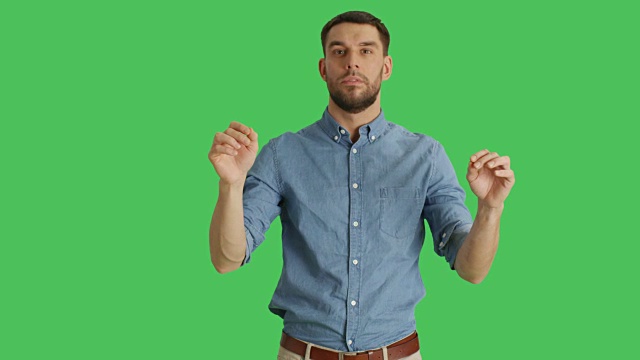 中等拍摄的一个随意的男人做滑动和触摸手势，而站在一个绿色的屏幕背景。视频素材