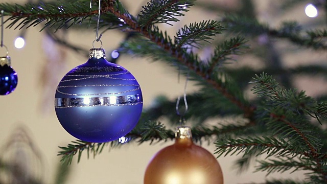 圣诞彩球上的云杉树枝上背景闪烁着灯光。视频素材