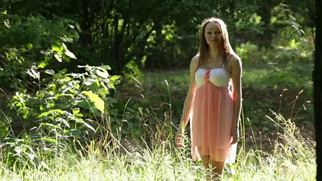 阳光明媚的女性肖像的花瓣在绿色的夏季森林林间空地的眼泪视频下载