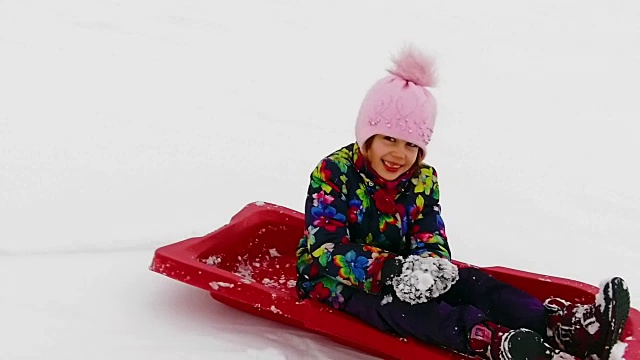 小女孩坐着雪橇从雪山上慢镜头滑下来视频下载