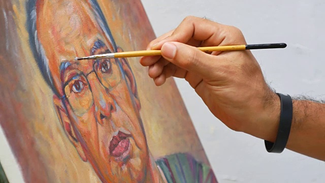 特写艺术家手握油漆笔刷画肖像的亚洲人视频下载