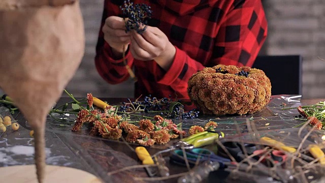 花商在木桌上制作花朵、浆果的组合视频下载
