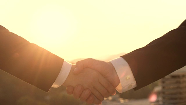 特写:企业家们在日落时分握手，象征着良好的伙伴关系视频素材