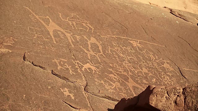 约旦瓦迪拉姆沙漠中描绘人类和骆驼的古代岩画视频素材