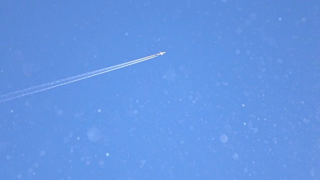 慢镜头:雪花在前面闪闪发光，一架飞机飞过天空视频素材
