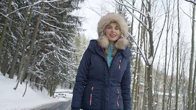 一个微笑的女人在雪地里享受冬天的肖像。视频下载
