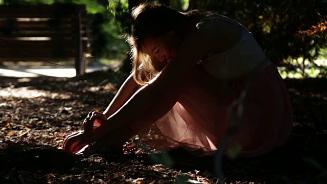 一个沉思的女性独自坐在夏天的公园穿着漂亮的衣服视频下载
