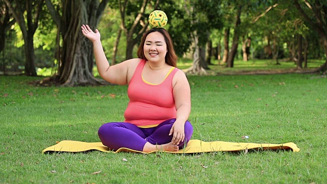漂亮的胖女人在垫子上玩藤球。视频下载
