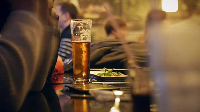 人们晚上坐在酒吧里喝啤酒。视频下载