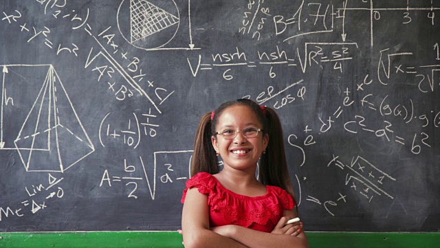 快乐的女孩在课堂上写黑板，面带微笑视频素材