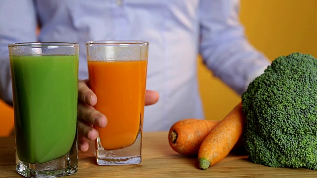 健康饮食，素食，饮食和排毒概念-女人的手把胡萝卜汁与蔬菜放在桌子上。视频下载