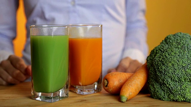 健康饮食，素食，饮食和排毒概念-女人的手把胡萝卜汁与蔬菜放在桌子上视频下载