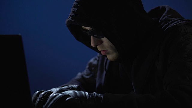 穿着黑衣，戴着墨镜和手套的奇怪男子正在从笔记本电脑中窃取数据视频下载