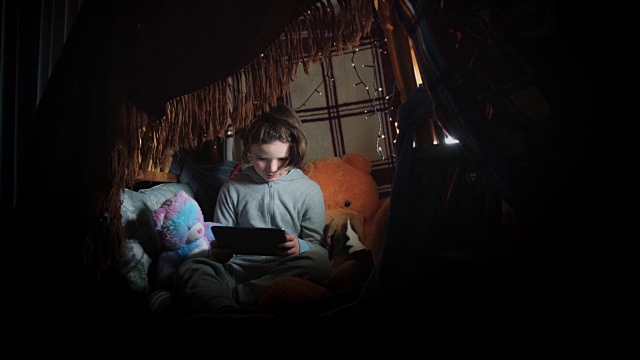 孩子在毯子下和他的狗在平板电脑上玩的4k照片视频素材