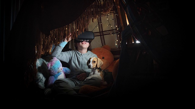 4k拍摄的孩子在毯子下与VR耳机和他的小狗视频素材