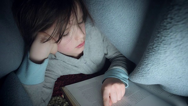 孩子在毯子下看书的4k镜头视频素材