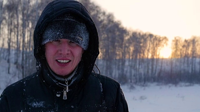 这家伙在冬天里，在夕阳下快乐地笑着。雪的冬天的风景。在户外视频下载