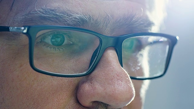 一个戴着眼镜和电脑屏幕的资深男性的特写。视频素材
