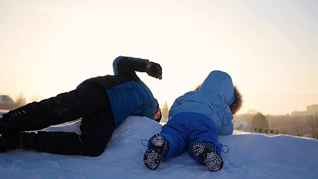 孩子们在雪山上玩耍。冬天的风景。日落时间视频素材