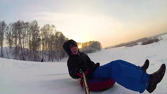 快乐的家伙骑着车，微笑着在雪道上玩雪车。缓慢的运动。雪的冬天的风景。在户外运动视频下载